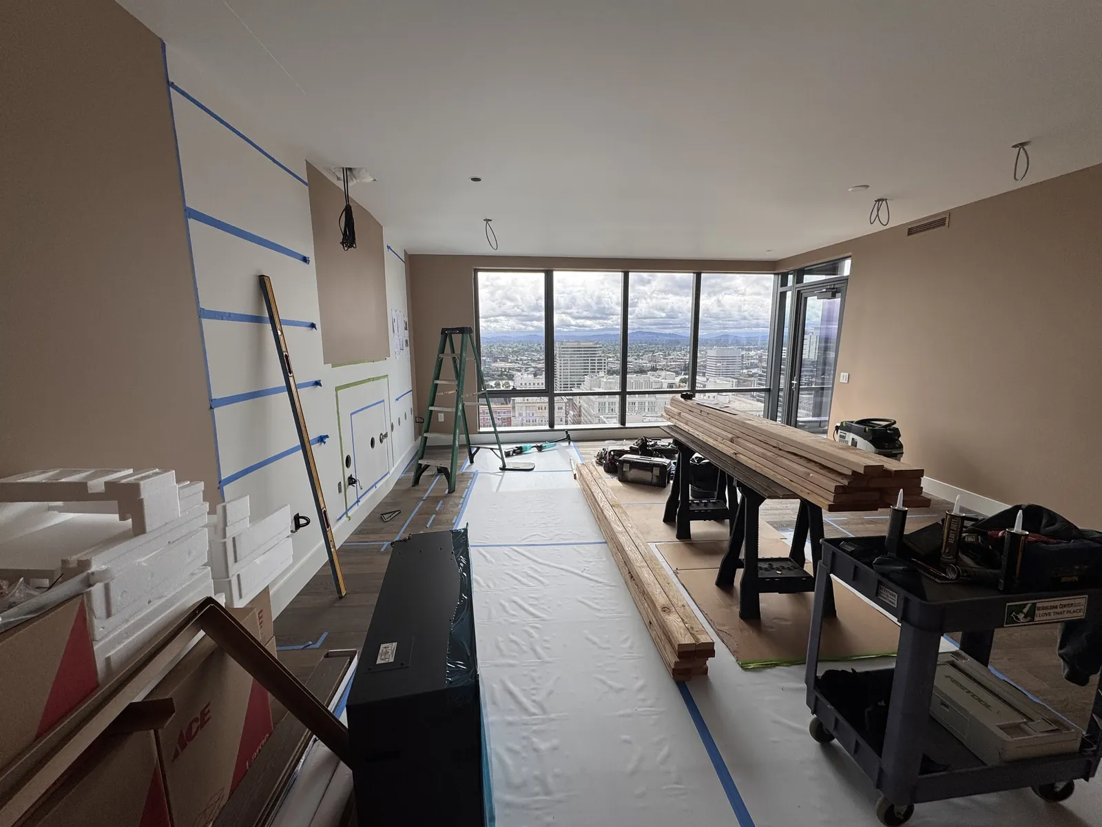Fireplace and built-ins, high-rise. Before: materials in, floors protected, and the view out the window